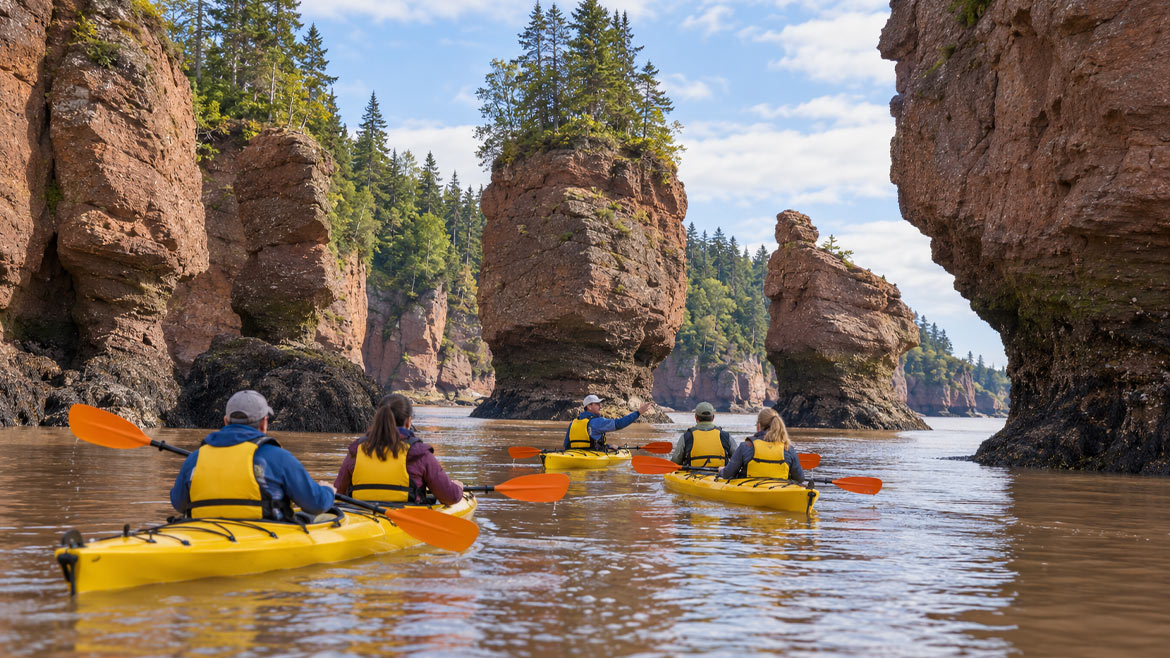 Guided kayakers paddling between Hopewell Rocks during high tide in the Bay of Fundy