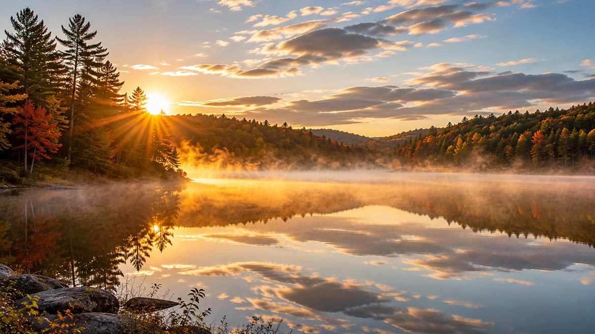 Sunrise over Canoe Lake with calm water and autumn forest in Algonquin Park
